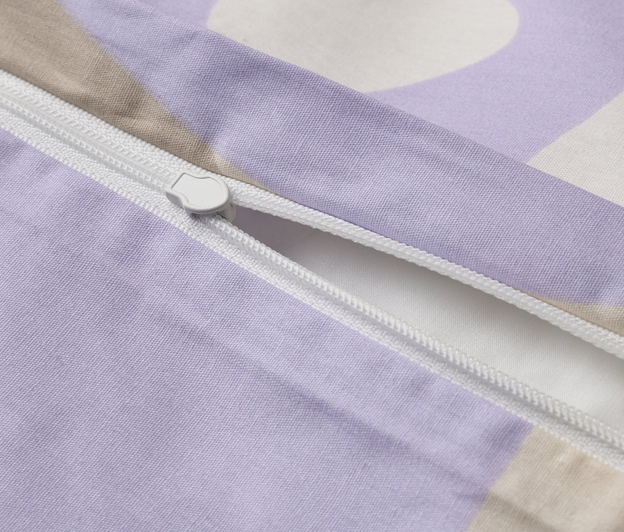 Gros plan d'une housse de couette violette à motifs partiellement ouverte avec une fermeture éclair blanche.