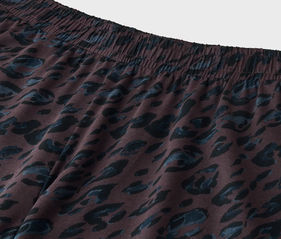 Gros plan d'un tissu marron foncé avec une taille élastique et un imprimé animal abstrait bleu foncé.