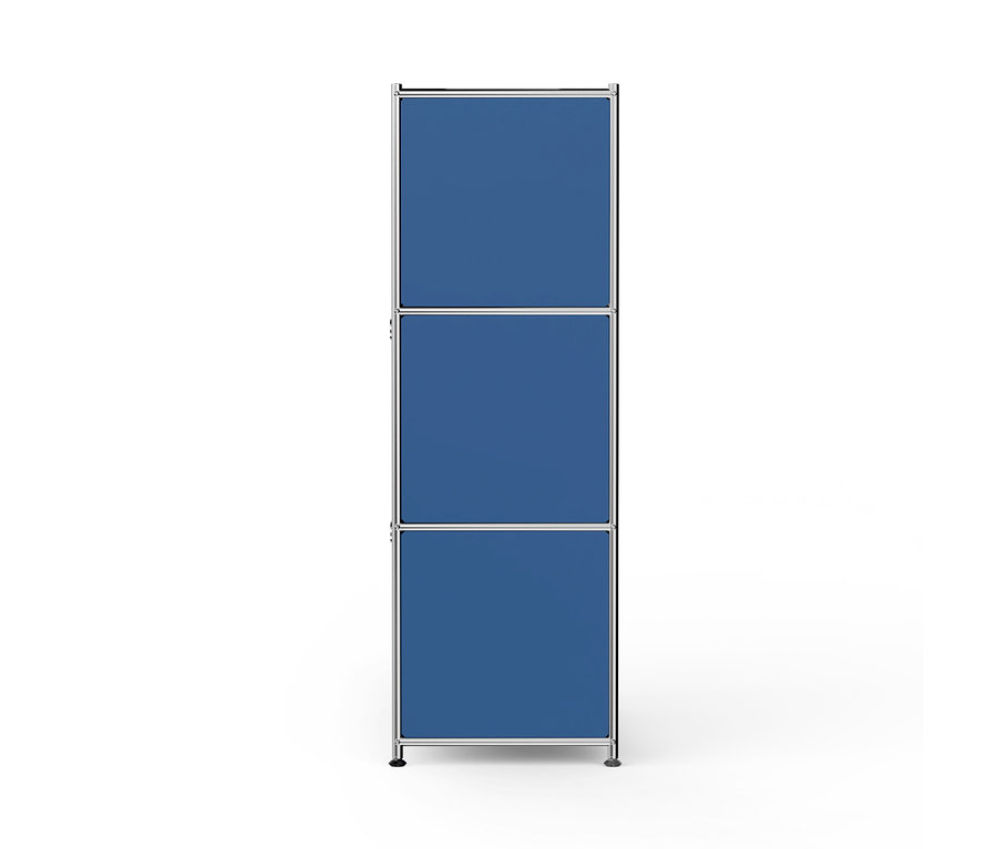 Une étagère modulaire haute et étroite avec un cadre argenté et trois compartiments rectangulaires bleus empilés, reposant sur de courts pieds foncés sur un fond blanc.