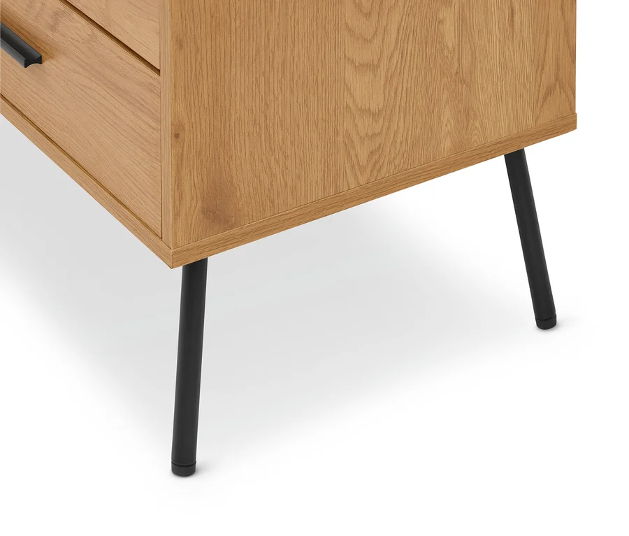 Gros plan d'un meuble en bois clair avec grain visible, doté d'une poignée noire sur un tiroir et de pieds noirs élancés.