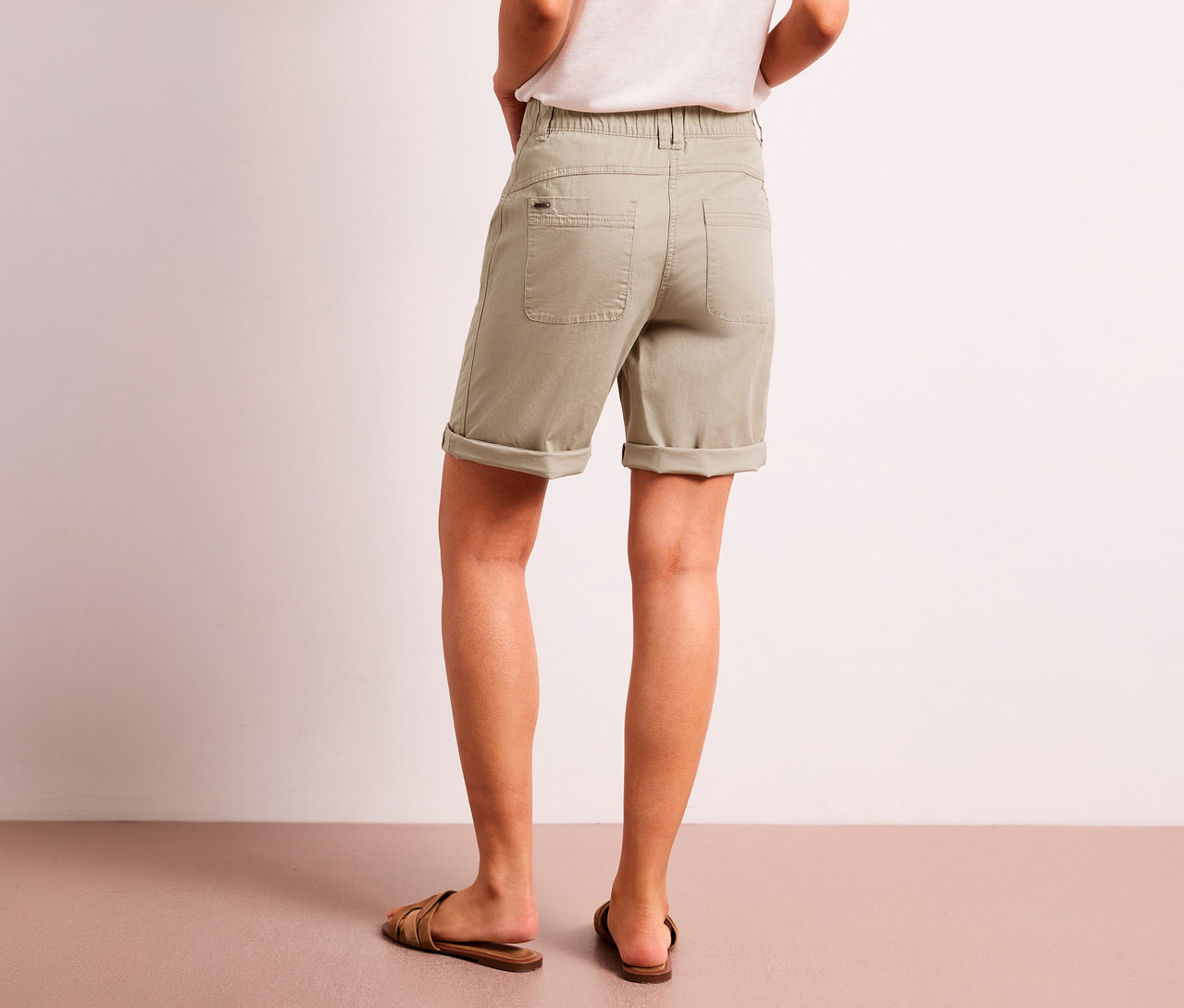 Une personne de dos, portant un bermuda Street One « Yulius » beige et des sandales marron.