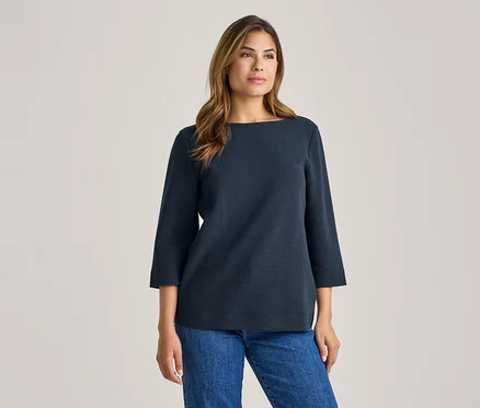 Femme portant un haut bleu foncé à manches 3/4 et un jean bleu.