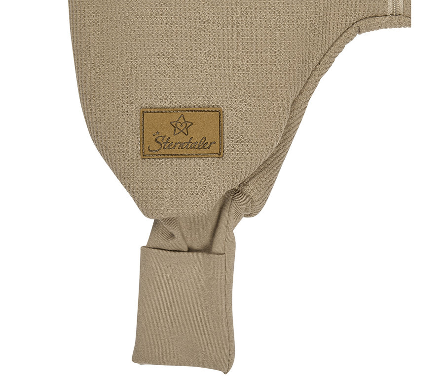 Bonnet bébé beige en maille gaufrée avec des protège-oreilles, orné d'une étiquette marron "Sterntaler" avec un logo étoile.