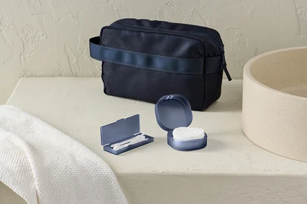 Sur la table, il y a une boîte de rangement et une trousse de toilette bleu foncé.