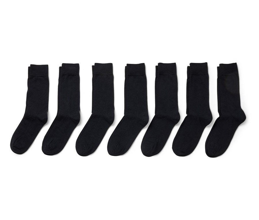 Sept paires de chaussettes noires alignées sur un fond blanc.