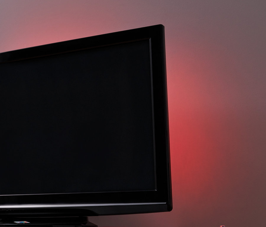 Téléviseur noir avec éclairage d'arrière-plan pour TV à LED sur une table blanche.