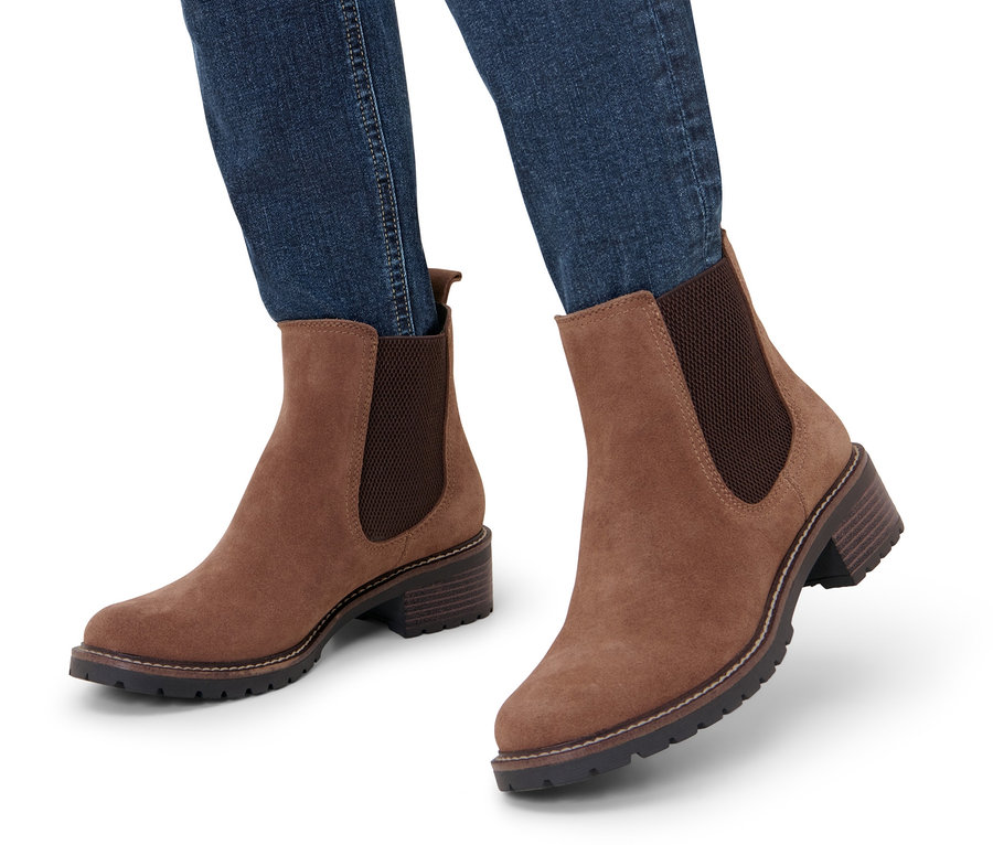 Jambes en jean portant des bottines en cuir velours.