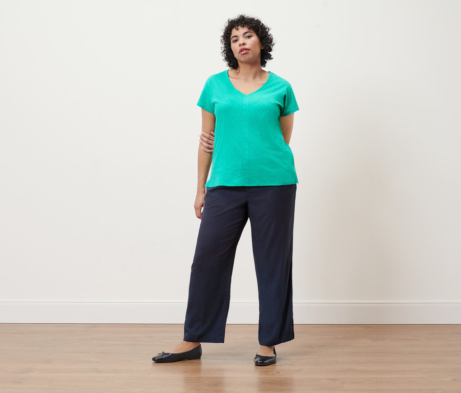 Une femme porte un t-shirt en lin mélangé aqua et un pantalon tissé bleu foncé.