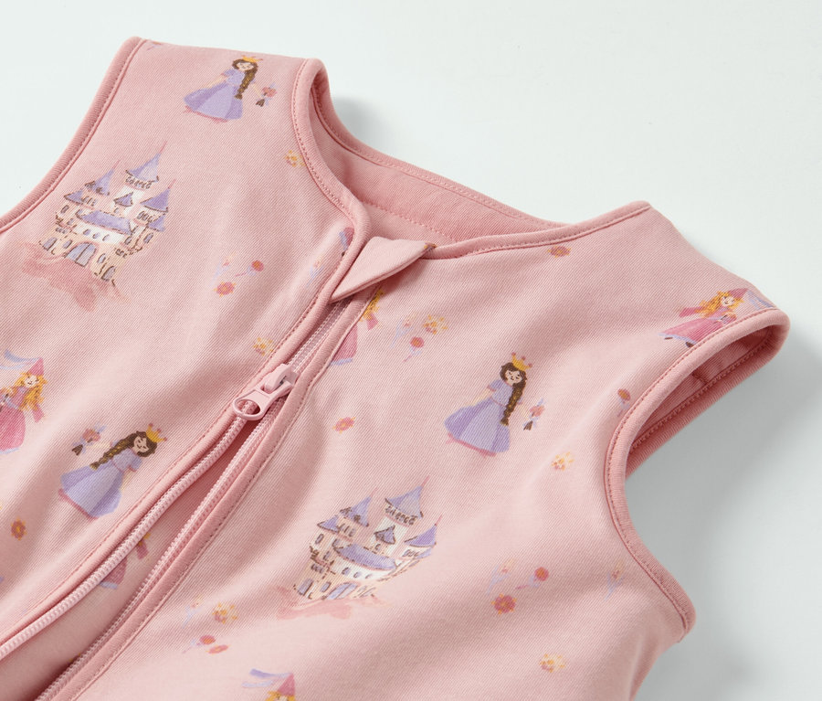 Gros plan sur une gigoteuse rose avec jambes, imprimée de princesses et de châteaux.