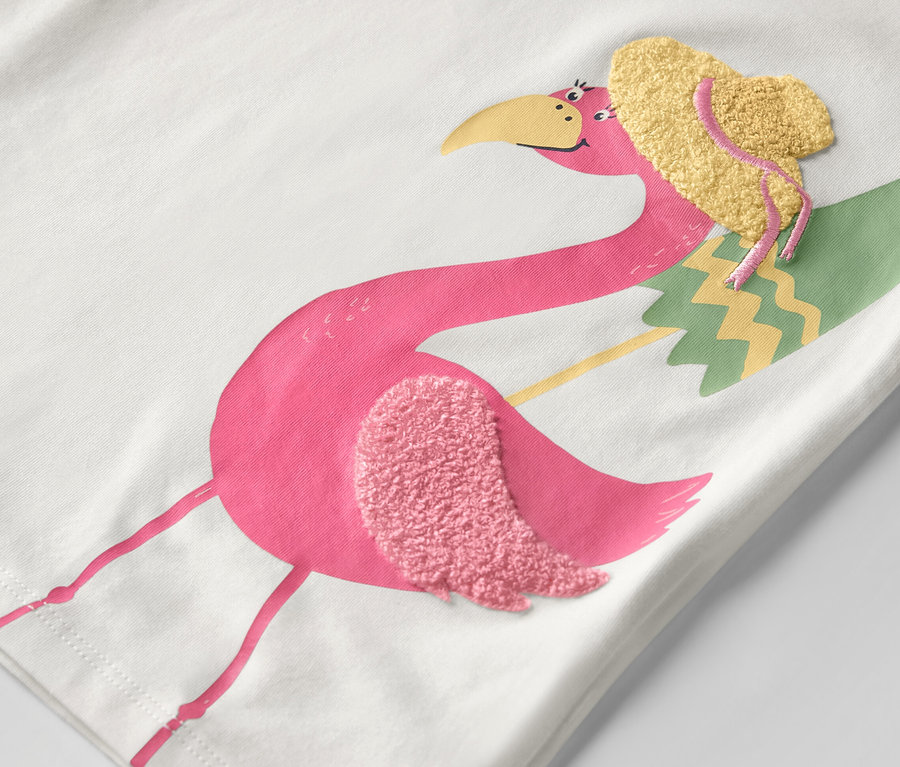 Gros plan sur un t-shirt pour enfant avec un motif flamant rose portant un chapeau.
