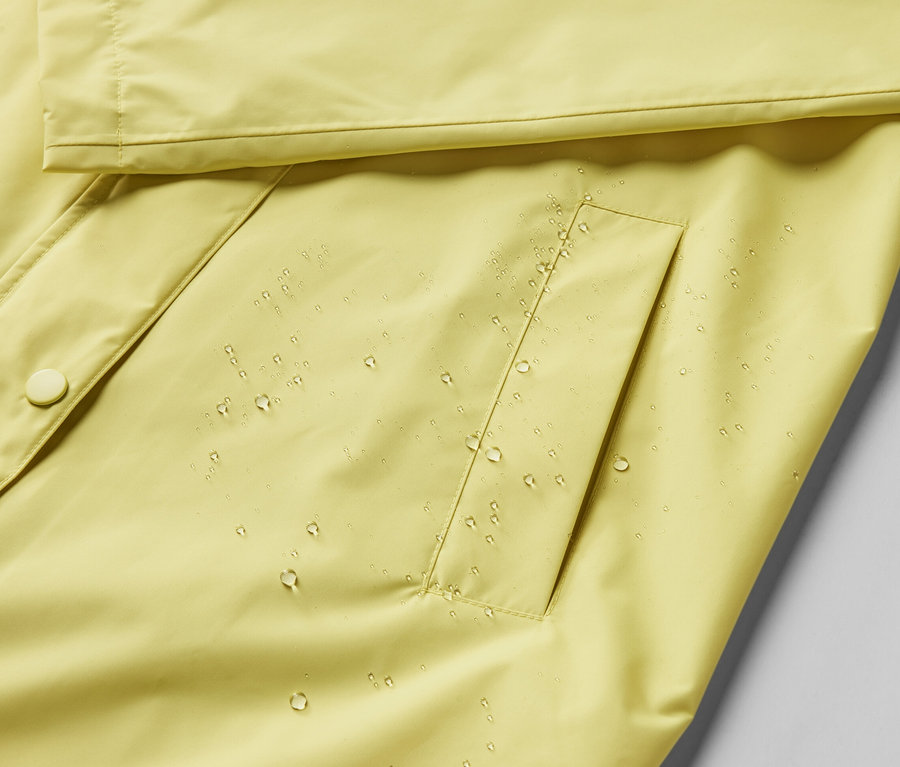 Gros plan sur une veste de pluie jaune avec des gouttes d'eau.