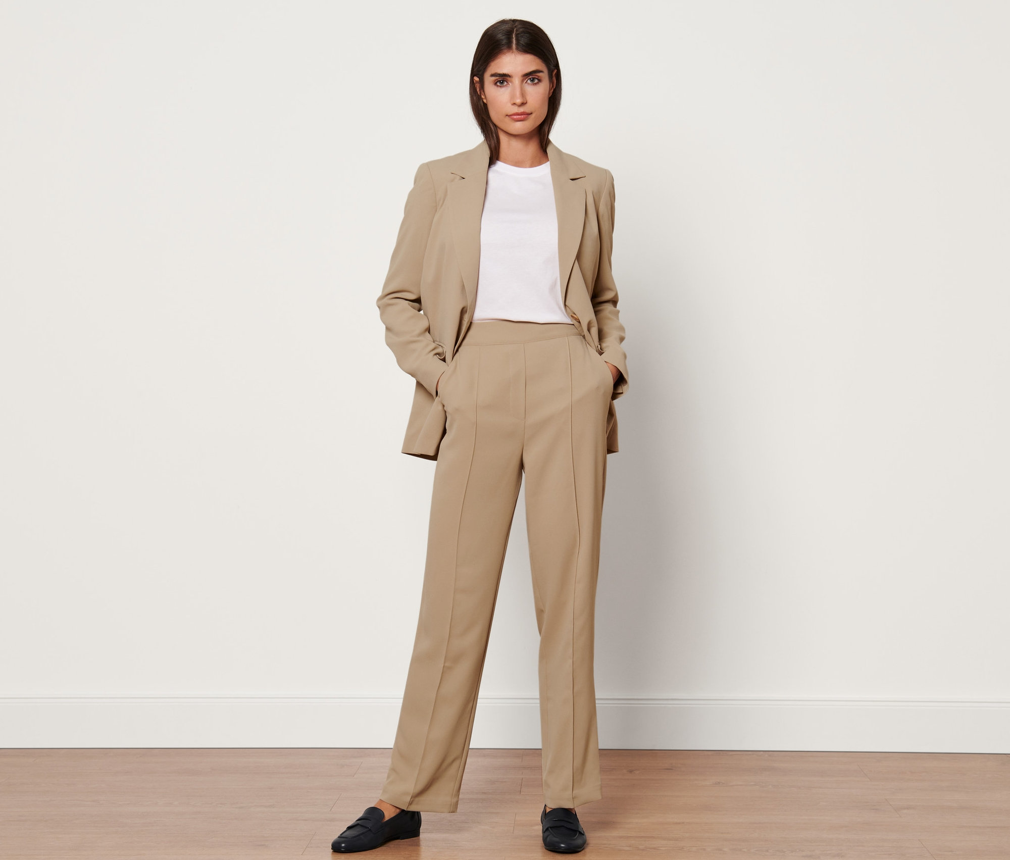 Femme posant dans un blazer beige et un pantalon tissé avec passepoil, beige.