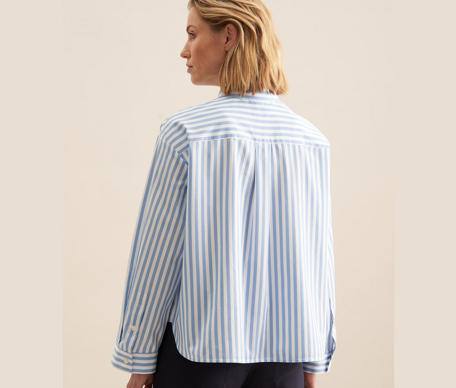 Vue arrière d'une femme blonde portant une chemise oversize bleue Seidensticker.