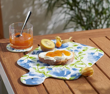 Un verre de confiture et une tartine de confiture sur une planche à servir.