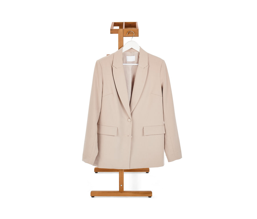 Un blazer beige est suspendu à un valet de nuit.