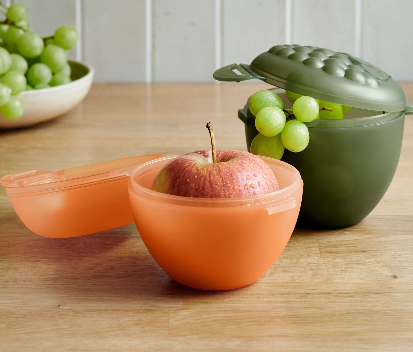 Pomme dans une boîte orange et raisins dans une boîte vert olive du set de boîtes pour pommes et raisins.