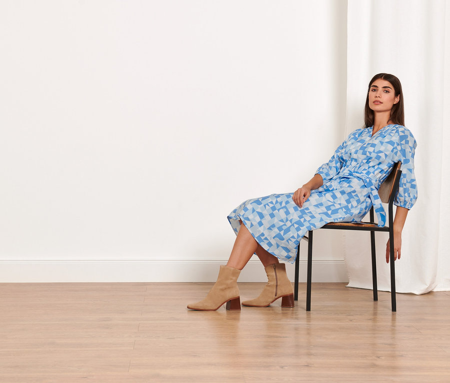 Une femme est assise sur une chaise et porte une robe tissée imprimée.