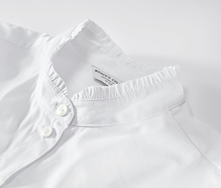 Gros plan sur un chemisier blanc avec des détails ruchés.