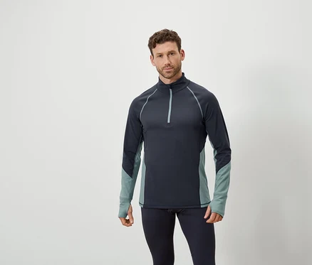 Un homme pose en haut à manches longues bleu marine zippé et leggings bleu marine.