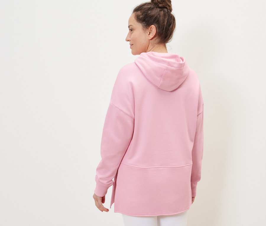 Femme portant un sweatshirt long à capuche, rose.