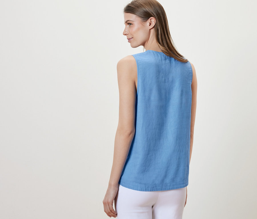Une femme, vue de dos, porte un chemisier sans manches en lin bleu clair.