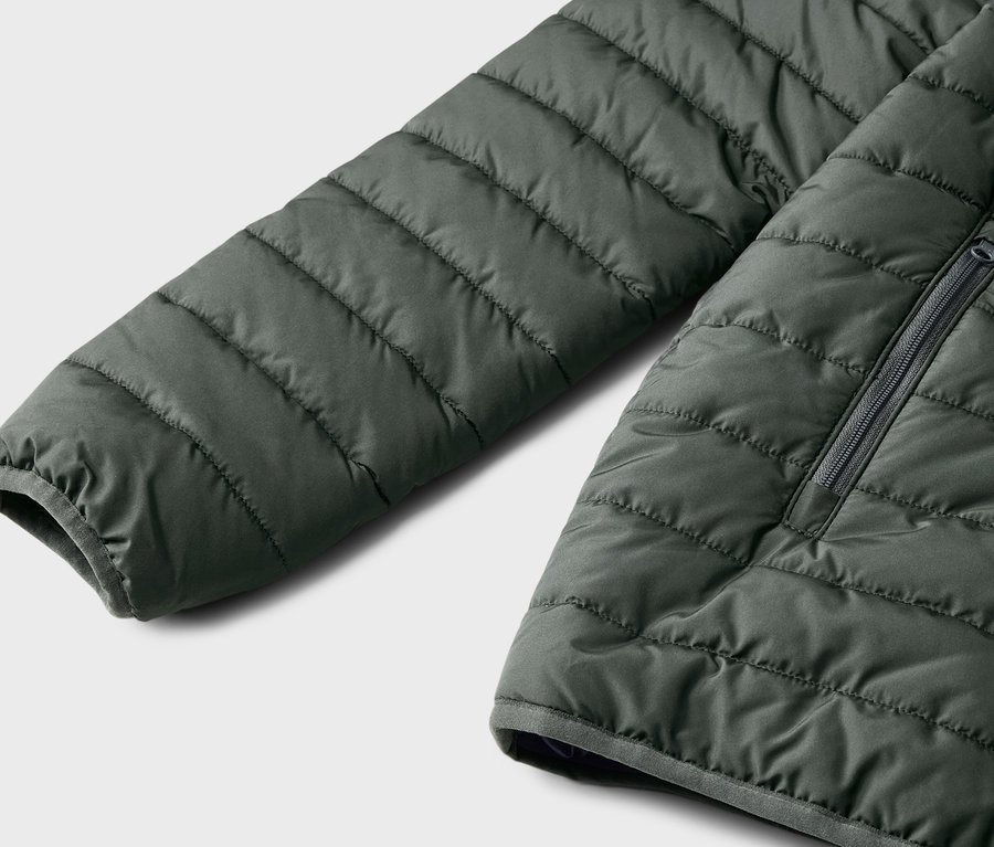 Gros plan sur une doudoune matelassée vert foncé pour enfant.