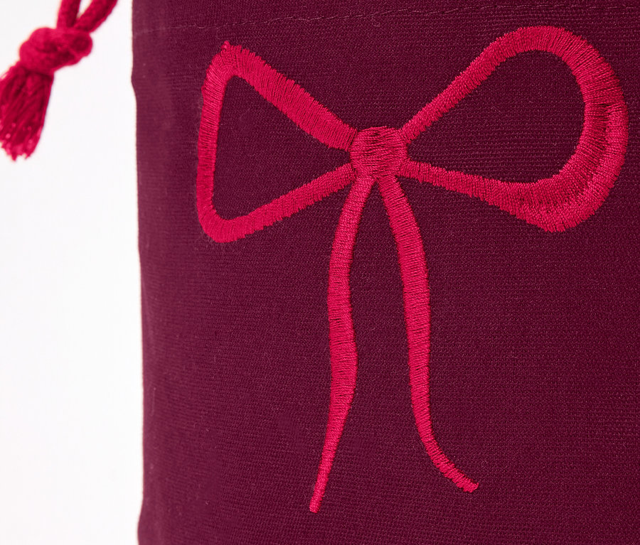 Gros plan sur un sac cadeau bordeaux avec un nœud rouge.