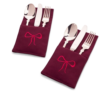 Deux ensembles de couverts dans des étuis en tissu bordeaux avec une broderie de nœud rouge.