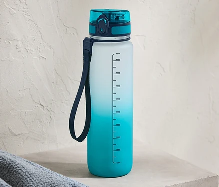 Une gourde bleue avec un dégradé de couleurs est posée sur une étagère en béton.