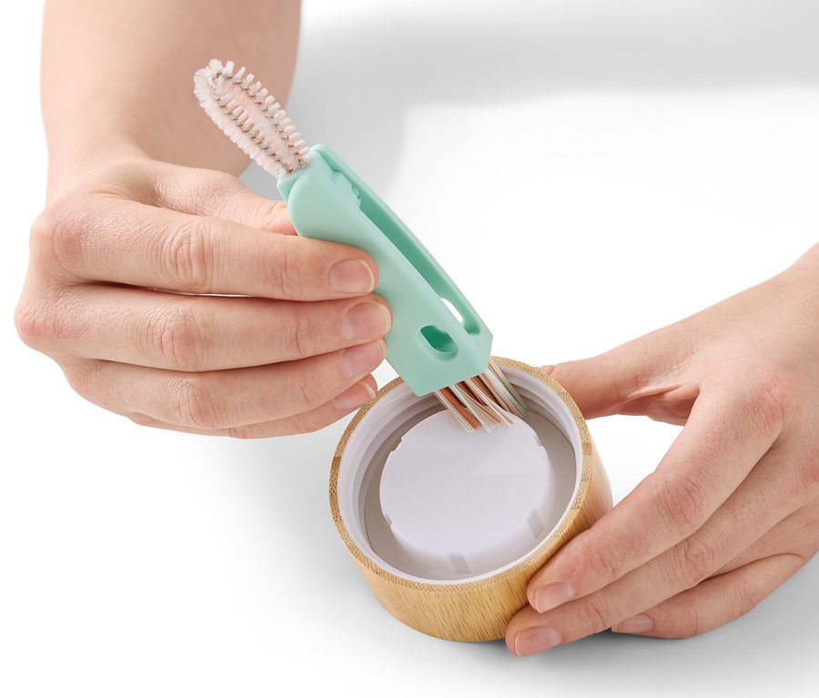 Des mains nettoient un couvercle de bouteille avec une brosse de nettoyage 3 en 1.
