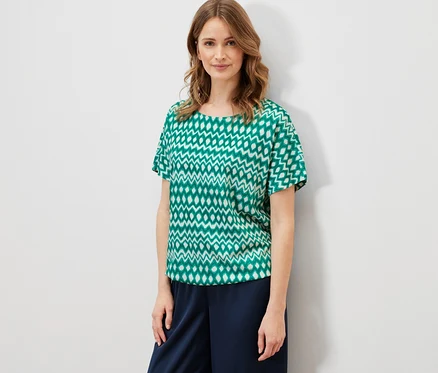 Une femme portant une blouse imprimée et un pantalon bleu marine.