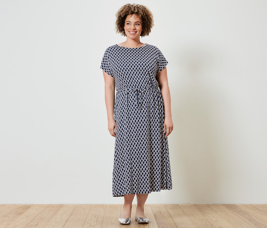 Femme debout portant une robe en jersey imprimée.