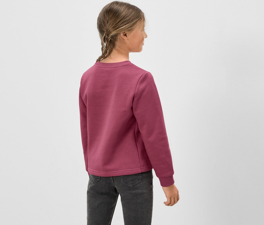 Une fille vue de dos, portant un sweat-shirt rose et un jean gris.