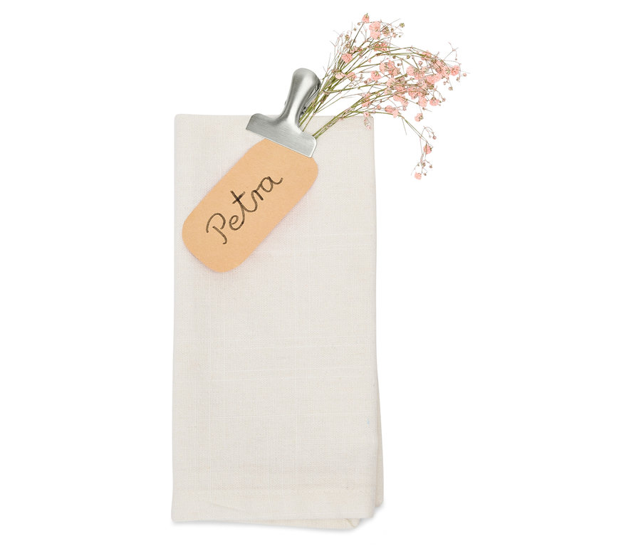 Serviette en tissu blanche pliée avec une étiquette nominative Petra et de petites fleurs roses.