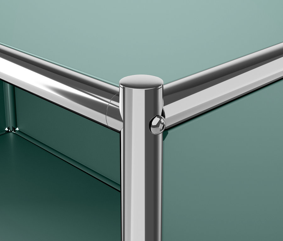 Détail d'un coin de meuble vert avec un pied chromé.