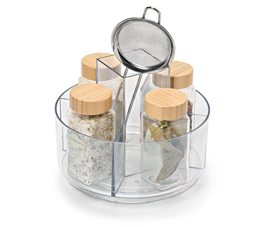 Cinq pots en verre avec couvercles en bois dans un support rotatif. Un pot contient du sel aux herbes, un tamis en acier inoxydable est sur le support.