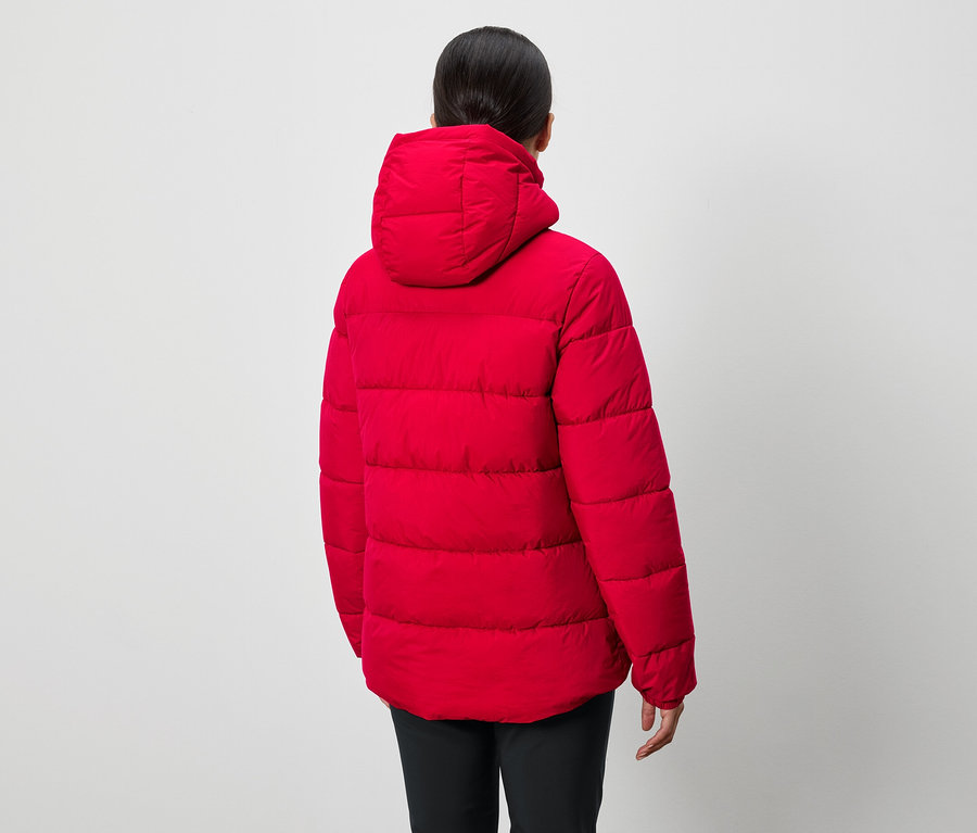 Une personne dos à la caméra porte un manteau rouge à capuche et un pantalon noir.