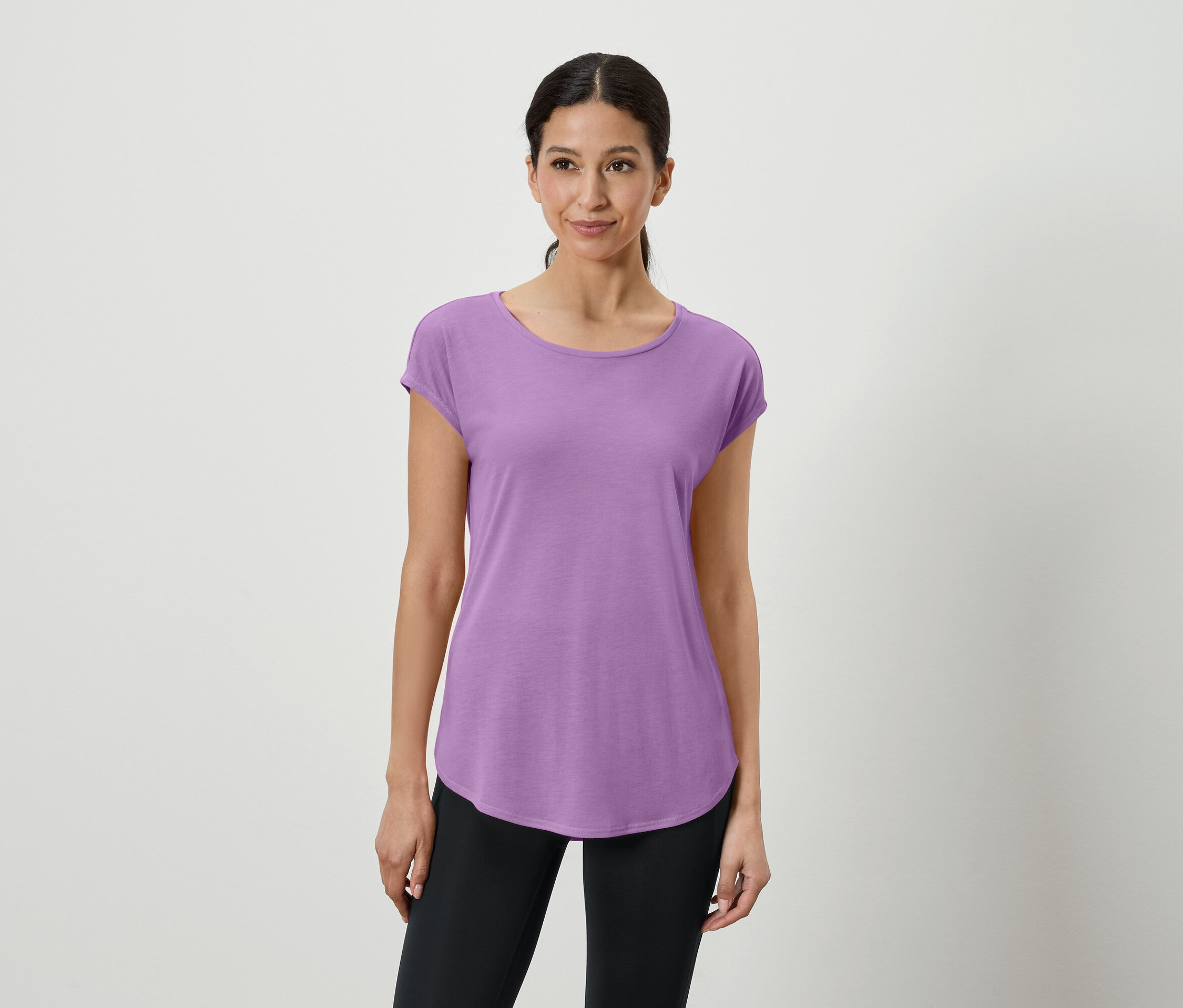 Une femme porte un t-shirt violet et un legging noir.