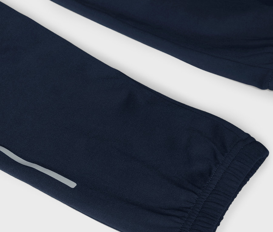 Gros plan sur un pantalon de survêtement bleu marine avec une bande réfléchissante.