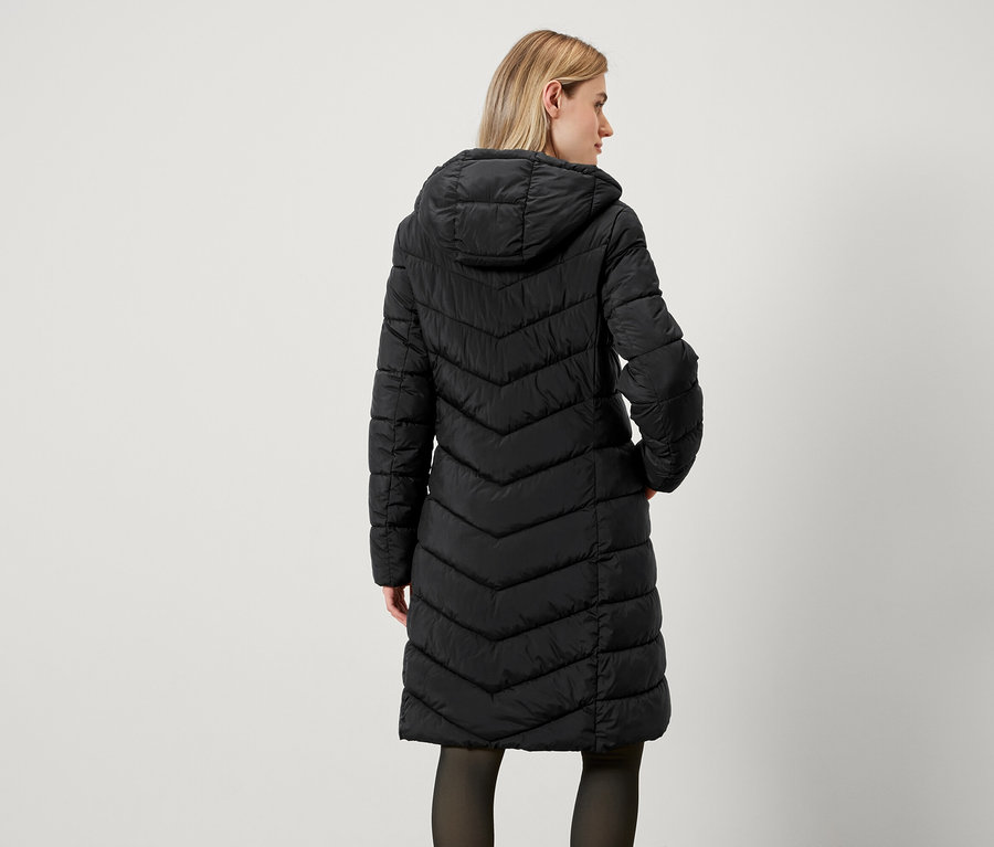 Vue arrière d'une femme portant un long manteau noir matelassé à capuche.
