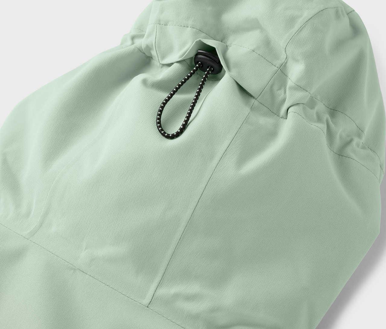 Gros plan sur la capuche d'une veste vert clair avec cordon de serrage.