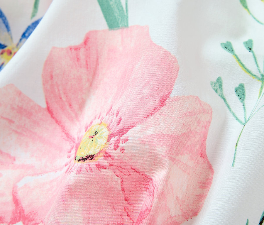 Gros plan sur un tissu blanc à motif floral, dominé par une grande fleur rose.