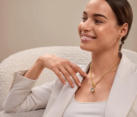 Une femme est assise et porte un collier et des boucles d'oreilles en or.