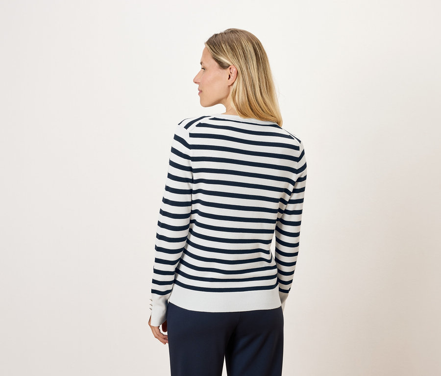 Blonde de dos portant un pull rayé à manches longues.