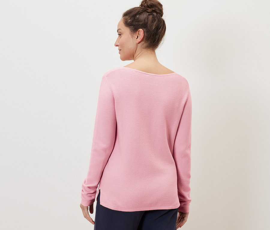Femme portant un pull en maille rose.