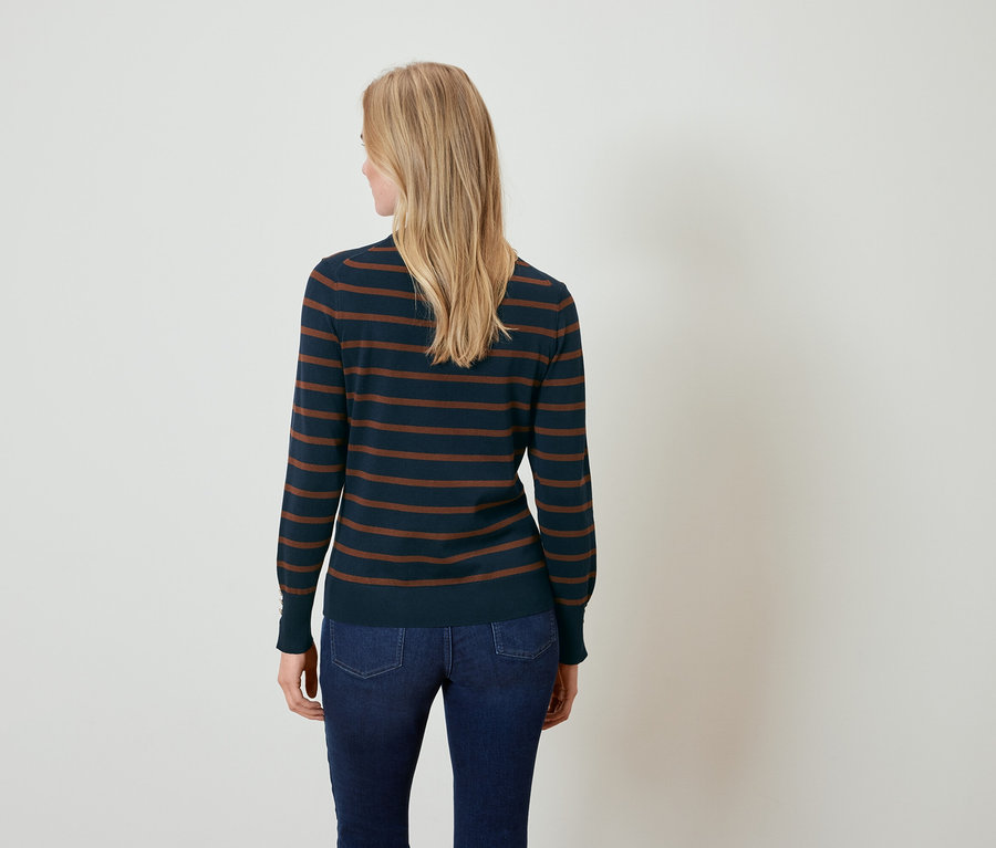 Une femme, vue de dos, porte un pull bleu marine rayé marron et un jean.