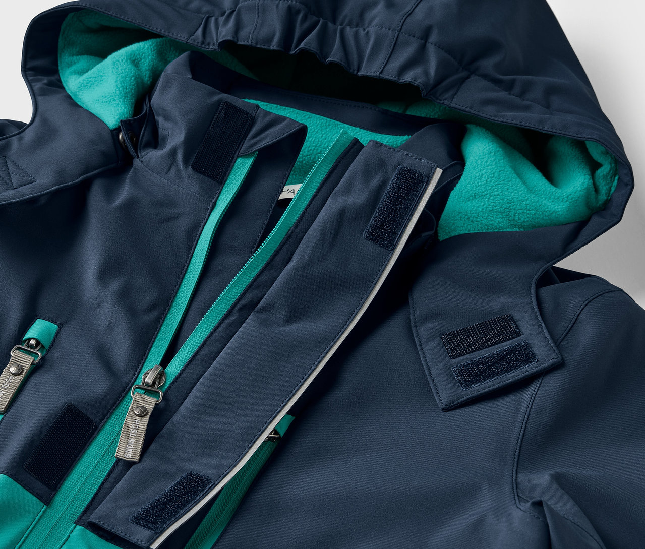 Gros plan sur une veste bleu marine à capuche avec une fermeture éclair verte.