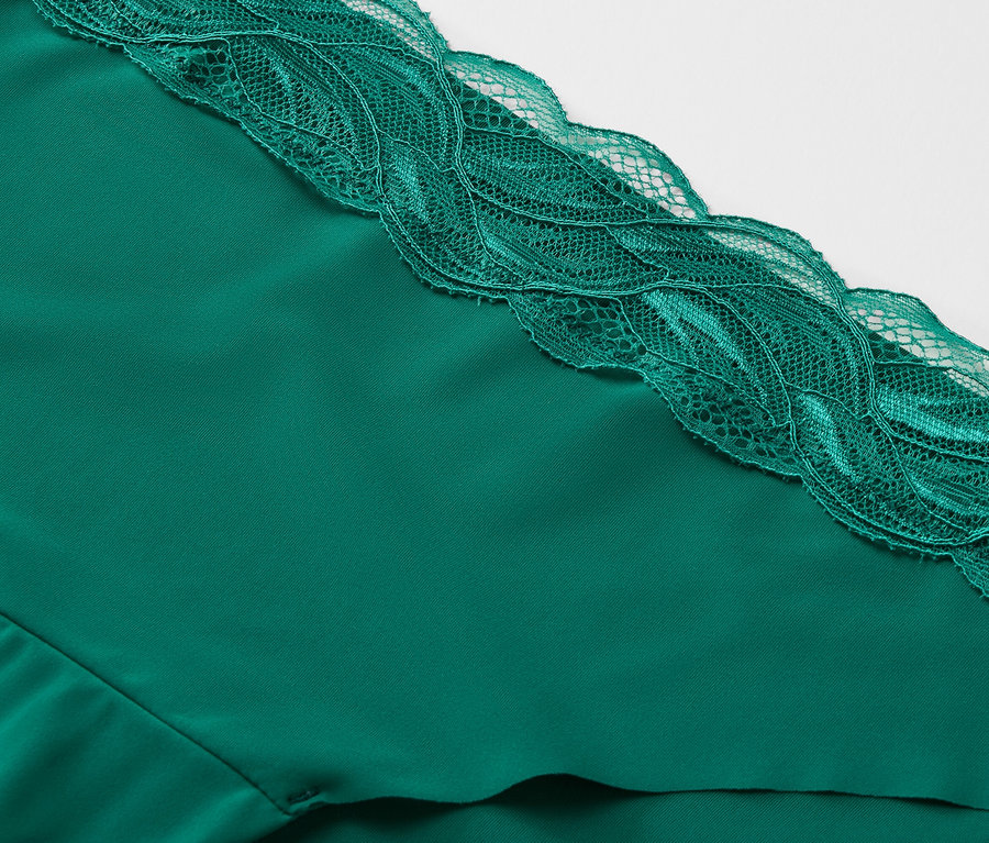 Gros plan d'un tissu vert émeraude avec une garniture en dentelle.