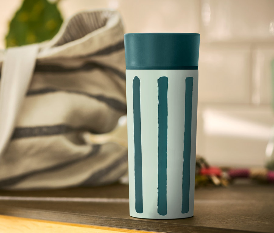 Un gobelet à café rayé est posé sur une table.