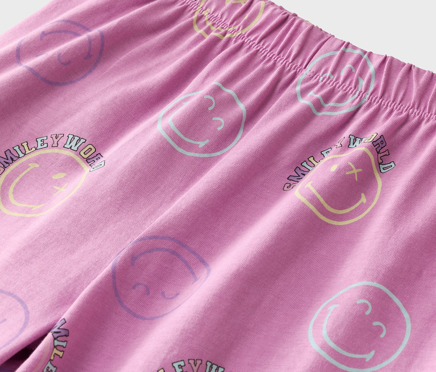 Gros plan d'un pantalon rose avec une taille élastique et des smileys colorés.